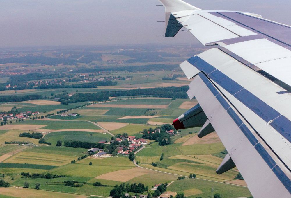 vista aerea de unos campos donde se ve parte del ala de un avión